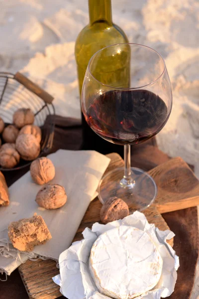 Hermosa composición romántica de vino tinto, pan y nueces en la playa de arena, de cerca —  Fotos de Stock