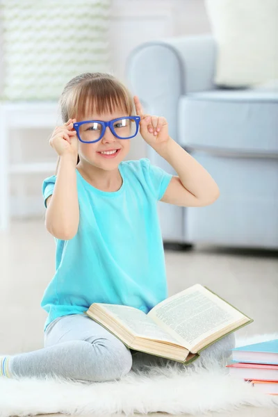 Menina sentada perto do sofá com livro — Fotografia de Stock