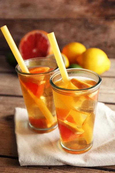 与柠檬和葡萄柚木制背景上的冰的茶 — 图库照片