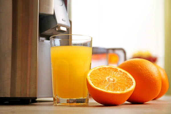 Odšťavňovač a pomerančový džus na kuchyňském stole — Stock fotografie