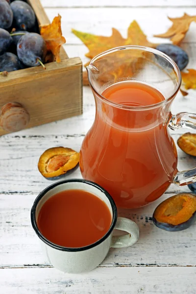 Suco de ameixa em jarra e caneca com frutas frescas — Fotografia de Stock