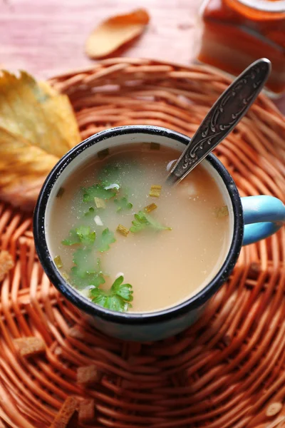 Mug of soup on wicker mat — Stock Photo, Image