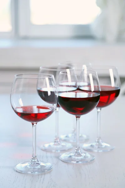 Copos de vinho tinto na mesa sobre fundo brilhante — Fotografia de Stock