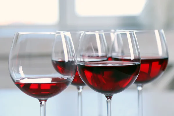 Bicchieri di vino rosso su tavola su sfondo brillante — Foto Stock