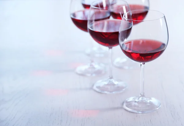 Vasos de vino tinto en la mesa sobre fondo brillante — Foto de Stock