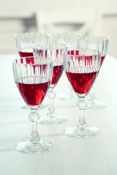 Vasos de vino tinto en la mesa sobre fondo brillante —  Fotos de Stock