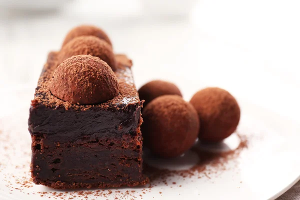 Rebanada de pastel de chocolate con una trufa en el primer plano del plato — Foto de Stock