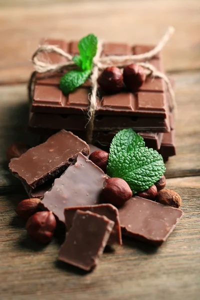 Schwarze Schokoladenstücke mit Nüssen auf Holzgrund — Stockfoto