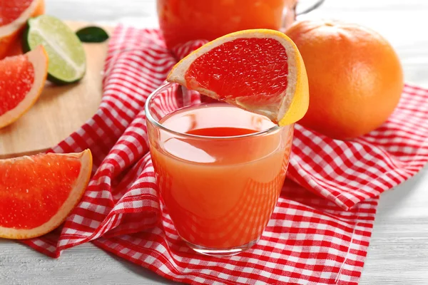 Vasetto di succo di agrumi e frutta fresca su fondo di legno chiaro — Foto Stock