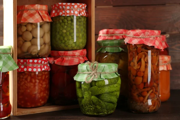 Jars with pickled vegetables and beans on wooden background — Stock Photo, Image