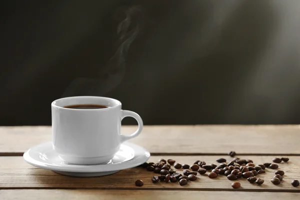 Copa de granos de café y café sobre mesa de madera, sobre fondo gris — Foto de Stock