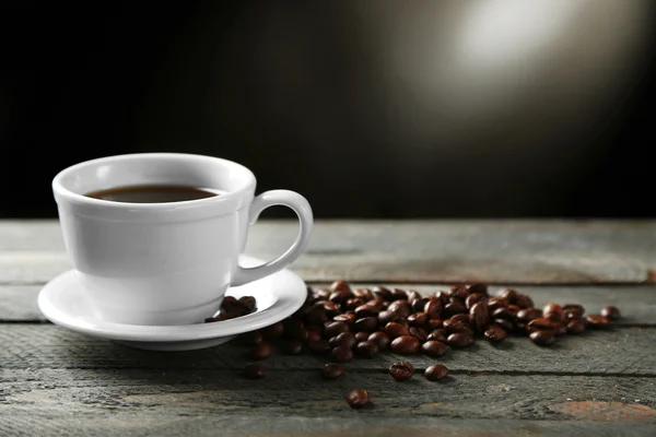 Tasse Kaffee und Kaffeekörner auf Holztisch, auf grauem Hintergrund — Stockfoto