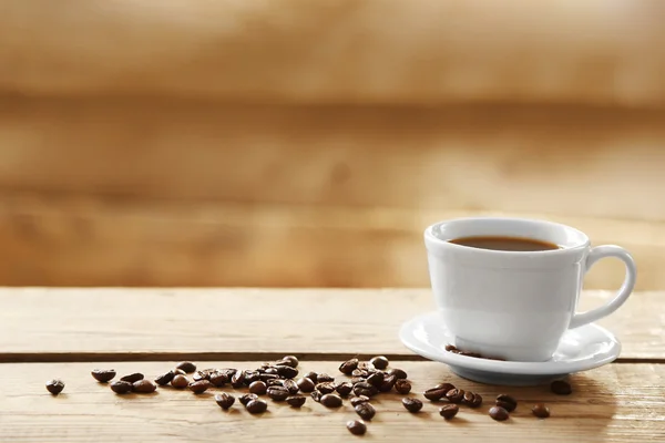 Tasse Kaffee und Kaffeekörner auf Holzgrund — Stockfoto