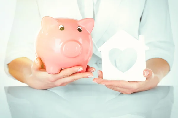 Woman holding house and piggy bank — Stock Photo, Image