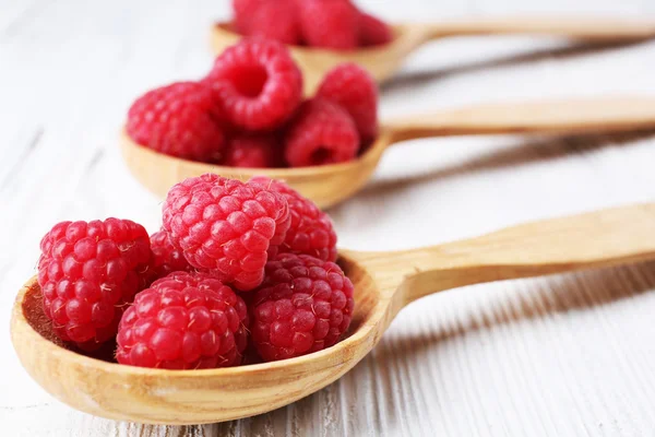 Frische rote Himbeeren in Löffeln auf Holztisch, Nahaufnahme — Stockfoto