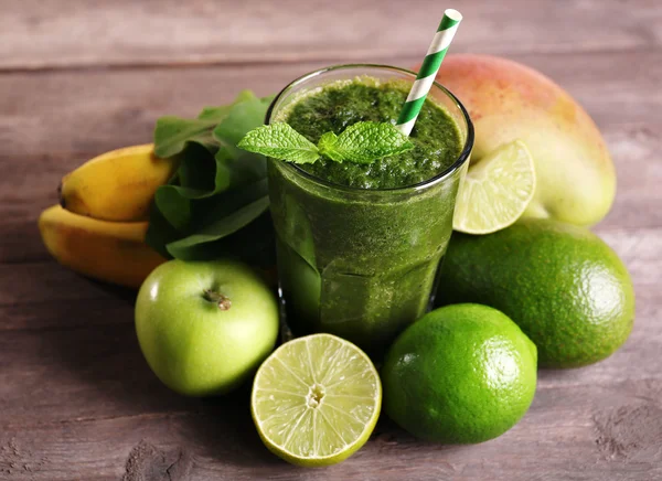 Green healthy juice with fruits and herbs on wooden table close up — Stock Photo, Image