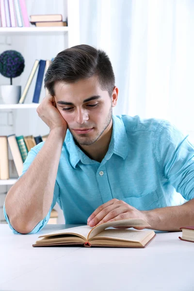 Young man reading book at table — Stock Photo, Image