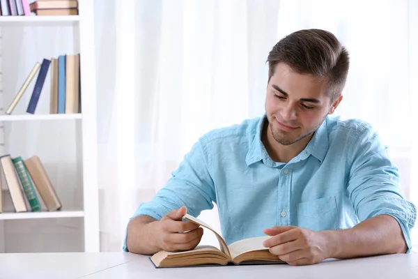 Jeune homme lisant un livre à table — Photo
