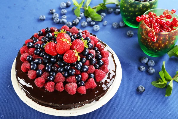 Delicious chocolate cake with summer berries on blue tablecloth background — Stock Photo, Image