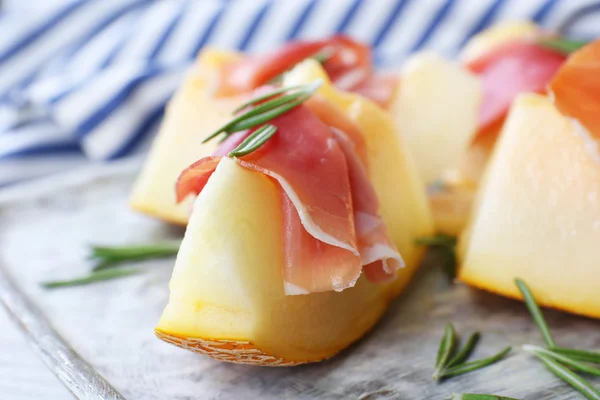 Melon with prosciutto of Parma ham on wooden table, closeup — Stock Photo, Image