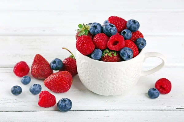 Tasty ripe berries in cup on wooden table close up — Stock Photo, Image