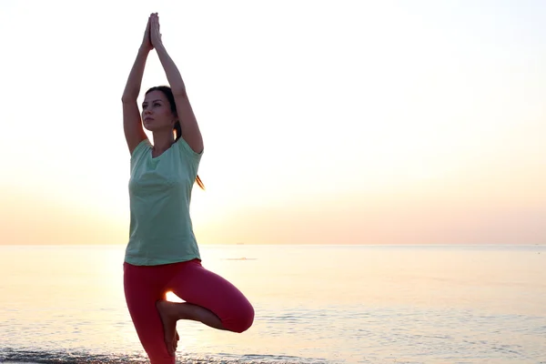 Vrouw doet yoga op het strand — Stockfoto