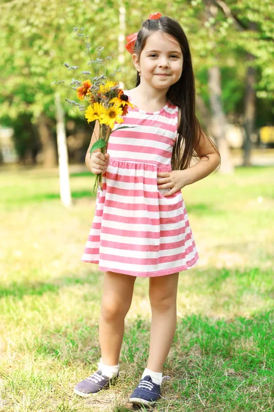 Glückliches kleines Mädchen mit Blumen — Stockfoto