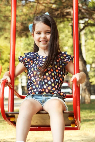 Happy little girl riding swings — Stock Photo, Image