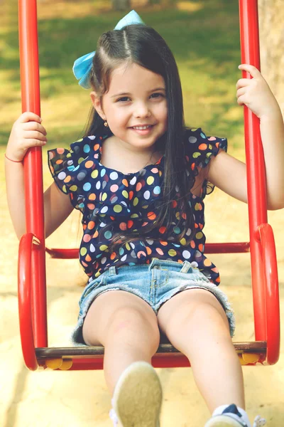 Счастливая маленькая девочка на качелях — стоковое фото