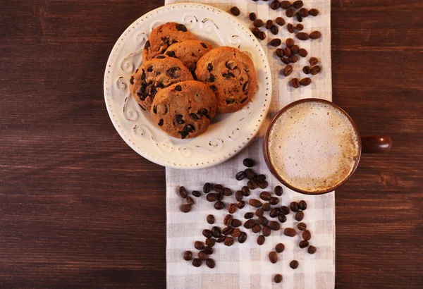 Cangkir kopi, kue lezat dan biji kopi tersebar di serbet, tampilan atas — Stok Foto