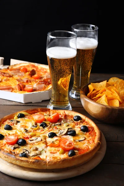 Pizza servida con cerveza sobre mesa de madera — Foto de Stock