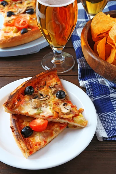 Plasterki pizzy serwowane z piwem na drewnianym stole — Zdjęcie stockowe
