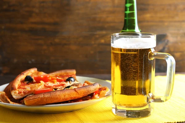Sliced pizza served with beer on wooden table — Stock Photo, Image