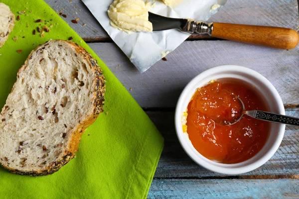 Confiture savoureuse dans le bol, beurre et pain frais sur une serviette verte close-up — Photo