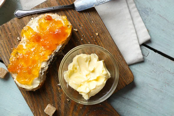 Gustoso pane fresco con marmellata e burro su sfondo di legno — Foto Stock