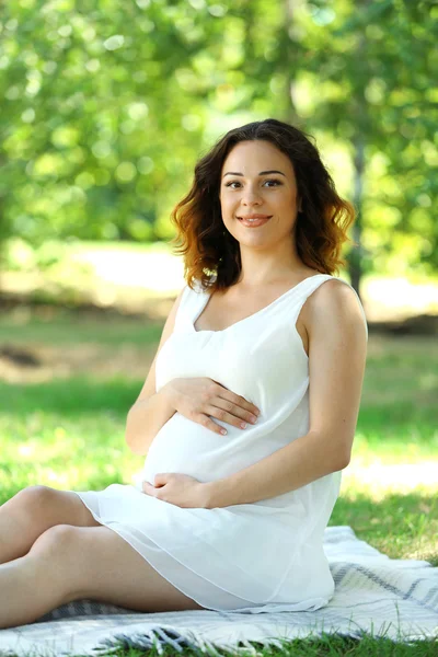 Wanita hamil di atas selimut di taman — Stok Foto