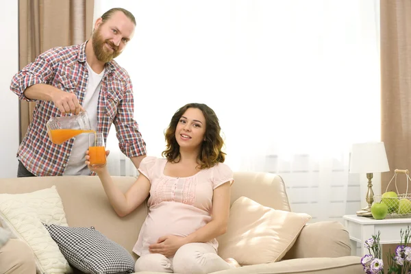 男は、彼の妊娠中の女性にジュースを与える — ストック写真