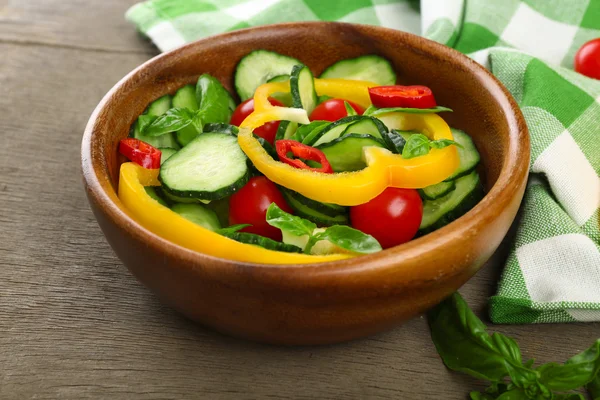 Vegetable salad with cucumbers  on wooden background decorated with green checked cotton serviette and sweet pepper — Stock Photo, Image