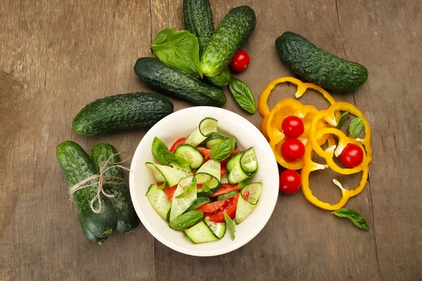 Vegetable salad with cucumbers and pepper on wooden background — Stock Photo, Image