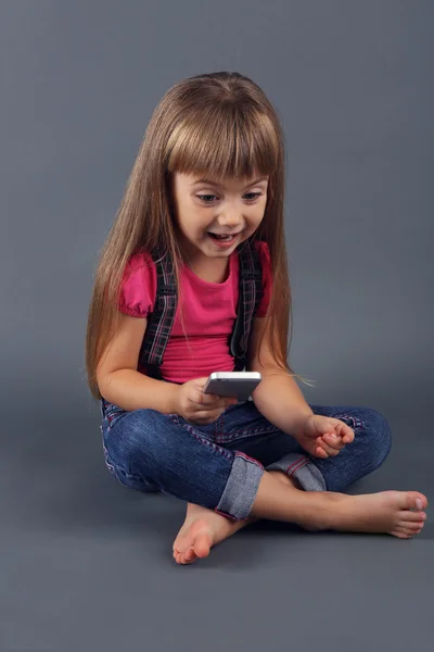 Красивая маленькая девочка с мобильным телефоном — стоковое фото