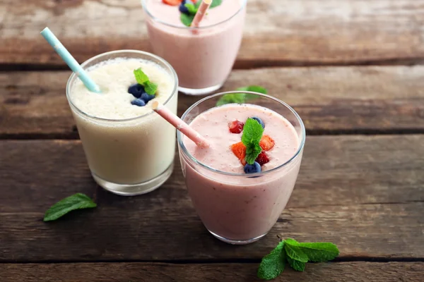 Frische Erdbeeren und Milchjoghurts mit Beeren auf Holzgrund — Stockfoto