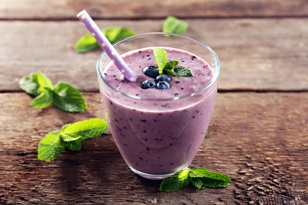 Chutné borůvkový jogurt s jahody a lístky máty na dřevěné pozadí — Stock fotografie