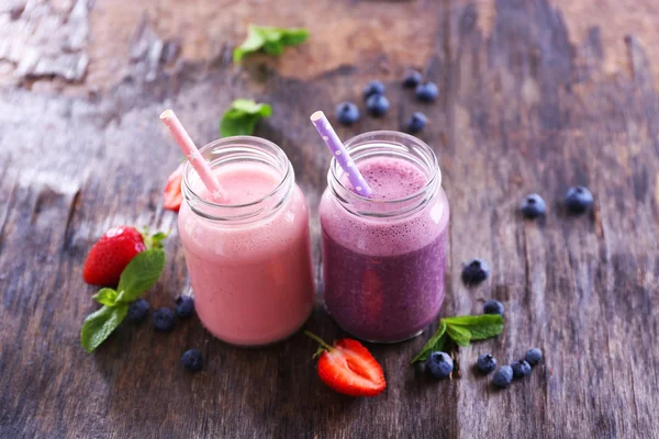 Yogurt alla fragola sano con menta e bacche intorno su sfondo di legno — Foto Stock