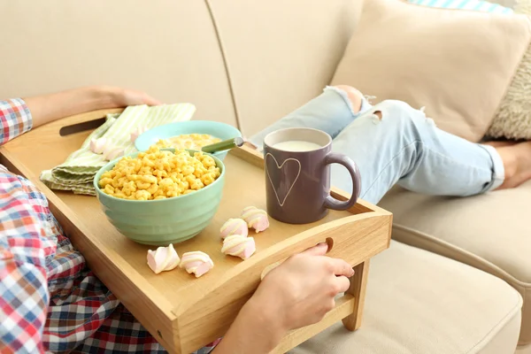 En tjej med en bricka med lunch på en soffa, närbild — Stockfoto