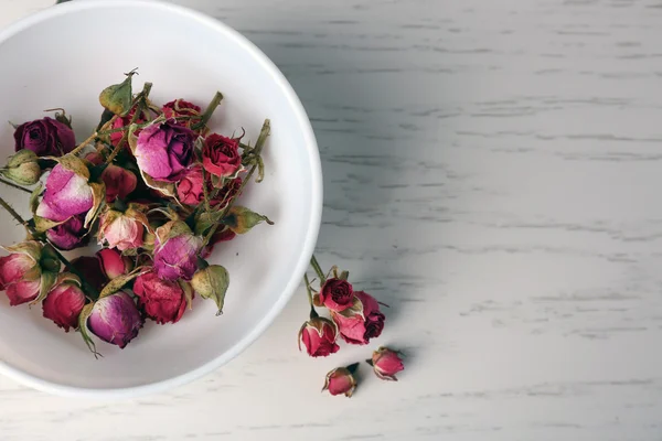 Tea rose in bowl on light wooden background — Stock Photo, Image