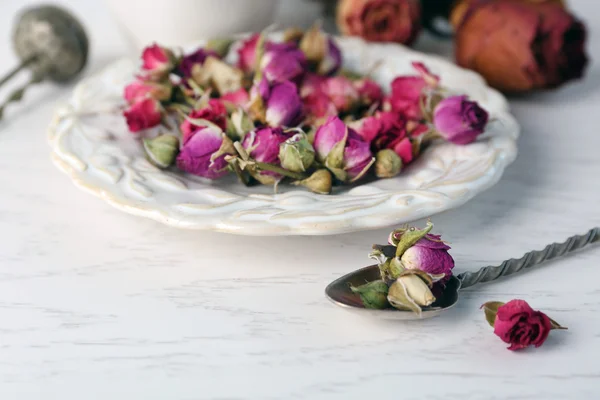 Tea rose flowers on plate on wooden table