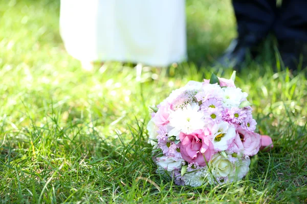 Свадебный букет на траве на фоне пары — стоковое фото