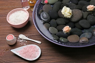 Spa kompozisyon çiçek ve su ahşap arka plan üzerinde taşlar