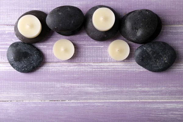 Spa composition of candles and stones on purple wooden background — Stock Photo, Image