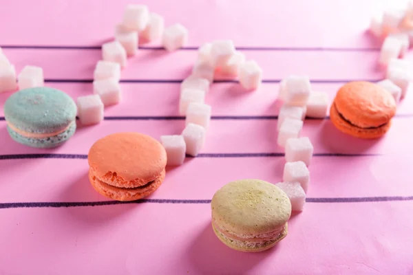 Creative beautiful music notes made of sugar and macaroons on pink background